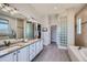 Bathroom with dual sinks, granite counters, tiled floors, glass brick accent, and separate tub and shower at 4781 Mariposa Rd, Castle Rock, CO 80104
