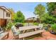 Outdoor patio with a wooden dining set, surrounded by lush greenery, creating a serene backyard ambiance at 5323 E Sandpiper Ave, Castle Rock, CO 80104