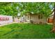 Quaint home with lush green lawn, mature tree, and a PODS moving and storage container in the driveway at 5323 E Sandpiper Ave, Castle Rock, CO 80104