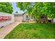 Charming home with a green lawn, mature trees, and a PODS moving and storage container in the driveway at 5323 E Sandpiper Ave, Castle Rock, CO 80104