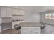 Open kitchen area with gray countertops, white cabinetry, and island with seating overlooking living area at 778 2Nd St, Firestone, CO 80520