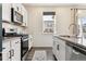 Bright kitchen showcasing white cabinets, stainless steel appliances, granite countertops, and hardwood flooring at 9 N Waterloo St, Aurora, CO 80018