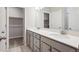 Bathroom with double sinks, quartz countertops, grey cabinetry, tile floor, and a view into the walk-in closet at 2277 Serenidad St, Brighton, CO 80601