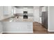 Modern kitchen featuring white cabinets, stainless steel appliances, granite countertops, and wood floors at 2134 Alyssa St, Fort Lupton, CO 80621