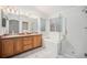 Bathroom featuring double sinks, walk-in shower, soaking tub, and wooden cabinets at 5607 S Gray St, Littleton, CO 80123