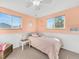 This charming bedroom includes light peach paint, a large window, white wainscoting and carpet, and a modern light fixture at 5747 W Elmhurst Ave, Littleton, CO 80128