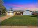 Inviting single-story home with vibrant lawn, covered porch, and garage, seen at twilight at 5747 W Elmhurst Ave, Littleton, CO 80128