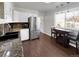 Sunlit eat-in kitchen features stainless steel refrigerator, dark countertops, and dark wood floors at 5747 W Elmhurst Ave, Littleton, CO 80128