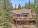 Rear exterior view showcases spacious deck with hot tub and outdoor seating area overlooking fenced area at 3726 Spring Valley Trl, Evergreen, CO 80439