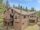 Multi-story home with wood facade, deck, and large windows surrounded by trees and sky at 3726 Spring Valley Trl, Evergreen, CO 80439
