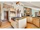 Bright kitchen with island cooktop, knotty alder cabinets, and a stone fireplace in the background at 3726 Spring Valley Trl, Evergreen, CO 80439