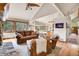 Open-concept living area with leather seating, a stone fireplace, and connecting views to the kitchen at 3726 Spring Valley Trl, Evergreen, CO 80439