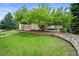 Charming brick home with a meticulously maintained front yard, mature tree, lush green lawn, and decorative brick retaining wall at 15756 E Aberdeen Ave, Centennial, CO 80016