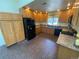 Well-lit kitchen with warm wood cabinetry, brick flooring, and modern black appliances at 7079 Estes Dr, Arvada, CO 80004