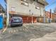 Parking lot featuring designated spots, brick facade, and blue trash receptacles at 1265 Colorado Blvd # 7, Denver, CO 80206
