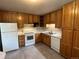 Functional kitchen equipped with oak cabinets, white appliances, and tile flooring, providing ample space for cooking at 6085 Simms St, Arvada, CO 80004