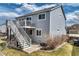 Backyard view of the gray two-story home with a deck, stairs, and concrete patio at 8459 Sweet Clover Way, Parker, CO 80134