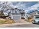 View of the two-story gray home with an attached garage and welcoming front porch at 8459 Sweet Clover Way, Parker, CO 80134