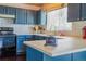 Charming kitchen boasts blue cabinets, light countertops, stainless appliances, and a bright window at 8459 Sweet Clover Way, Parker, CO 80134