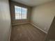 Cozy bedroom features neutral paint, plush carpet, and a large window overlooking the street at 18328 E 93Rd Pl, Commerce City, CO 80022