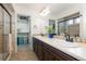 Bathroom with walk-in closet, double sinks, wood cabinets and framed mirror at 5480 Danube St, Denver, CO 80249