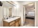 Neat bathroom with a vanity, mirror, and access to another bedroom at 5800 Tower Rd # 103, Denver, CO 80249