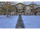 Front view of building with snowy landscaping at 5800 Tower Rd # 103, Denver, CO 80249