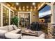 Relax on this cozy covered patio with a fire pit, comfortable seating, and views of the lush backyard at 10698 Mountaingate Ct, Littleton, CO 80126