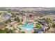 Aerial view of community pool featuring a multi-pool system, clubhouse, and adjacent parking, surrounded by natural landscape at 10698 Mountaingate Ct, Littleton, CO 80126
