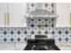 Close-up of kitchen backsplash and stove with pot filler featuring a blue and white star pattern design at 3640 Forest St, Denver, CO 80207