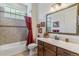 Bathroom featuring a tub with red shower curtain, vanity with a large mirror, and decorative pictures on the wall at 6948 W Jewell Dr, Lakewood, CO 80227