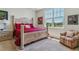 Bedroom featuring bright light from a large window and a light colored bed frame with red bedding at 6948 W Jewell Dr, Lakewood, CO 80227