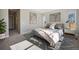 Modern staged bedroom with a plush bed, side tables, decorative art, and neutral colored walls at 17054 Hop Clover Ave, Parker, CO 80134