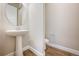 Stylish half bathroom features a pedestal sink, round mirror and wood floors at 17054 Hop Clover Ave, Parker, CO 80134