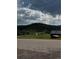 Picturesque view of a charming country home and barn nestled in a lush, green landscape with rolling hills and a dramatic sky at 27447 Upper Cold Spg Gulch Rd, Golden, CO 80401