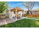 A backyard with a wooden pergola, outdoor dining area, lush lawn, and charming brick details at 1474 S Emerson St, Denver, CO 80210