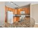 Well-lit kitchen featuring granite counters, wood cabinets, and modern white appliances at 9079 E Panorama Cir # 520, Englewood, CO 80112