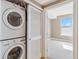 A laundry area with a stacked washer and dryer, near a room with neutral paint and carpeting at 9079 E Panorama Cir # 520, Englewood, CO 80112