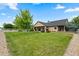Lush green backyard featuring mature trees, a manicured lawn, and covered patio at 8007 Sunrise Cir, Frederick, CO 80516
