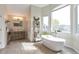 Bright bathroom featuring a soaking tub under a large window with a modern vanity at 10773 Cougar Rdg, Lone Tree, CO 80124
