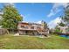 Large backyard features a spacious deck, patio area, mature trees, and green grass at 3390 S Ensenada Way, Aurora, CO 80013