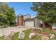 Side view of a charming home with a two-car garage, lush trees, and well-maintained landscaping at 3390 S Ensenada Way, Aurora, CO 80013