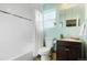 Bright bathroom featuring a shower over tub with white tiles, light green walls, and a dark wood vanity at 3471 W Exposition Ave, Denver, CO 80219