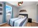 Bright bedroom with a mountain-themed wood headboard and light blue window coverings at 3471 W Exposition Ave, Denver, CO 80219