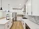 Elegant kitchen featuring white cabinets, stainless steel appliances, a herringbone backsplash, and an island with a sink at 42974 Colonial Trl, Elizabeth, CO 80107