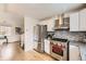 Modern kitchen featuring stainless steel appliances, granite countertops, white cabinetry, and hardwood floors at 9120 W Bellwood Pl, Littleton, CO 80123