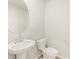 Bathroom features a pedestal sink, round mirror and white toilet at 20982 E 66Th Ave, Aurora, CO 80019