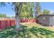 Spacious backyard featuring a lush lawn, privacy fence, and mature trees, ideal for outdoor activities at 5480 W Iowa Ave, Lakewood, CO 80232