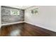 Bedroom featuring a wood accent wall, two windows, and hardwood floors at 5480 W Iowa Ave, Lakewood, CO 80232