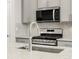 Modern gas range with stainless steel backsplash, microwave and gray cabinets at 742 N Tempe St, Aurora, CO 80018